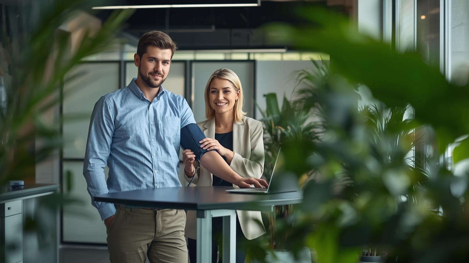 Mitarbeiter lässt am Stehschreibtisch Blutdruck messen